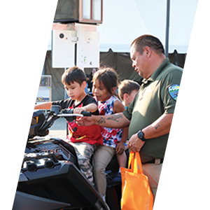 Officer demonstrating a patrol motorcycle to children at a community even